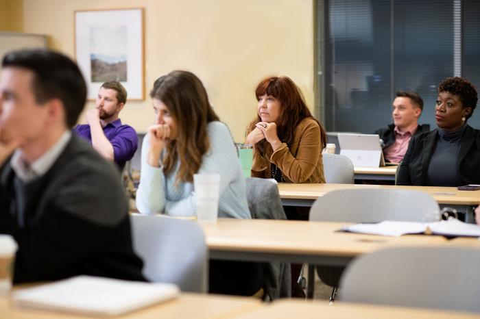 Graduate students sitting in classroom listening to instruction